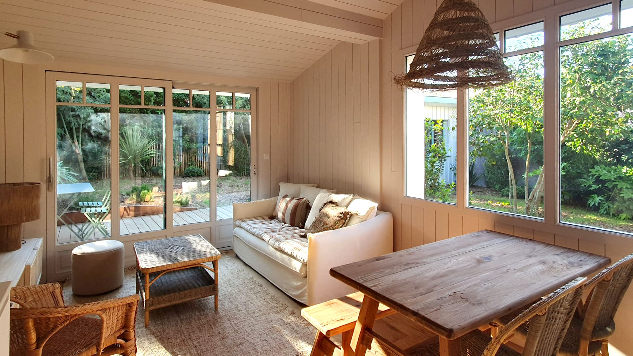 Zona living di casa vacanze a Cap Ferret con ampie vetrate, arredi naturali e cucina su misura Zecchinon progettata da Quartier Cuisine